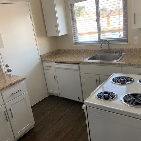 A kitchen with white cabinets and a granite countertop.